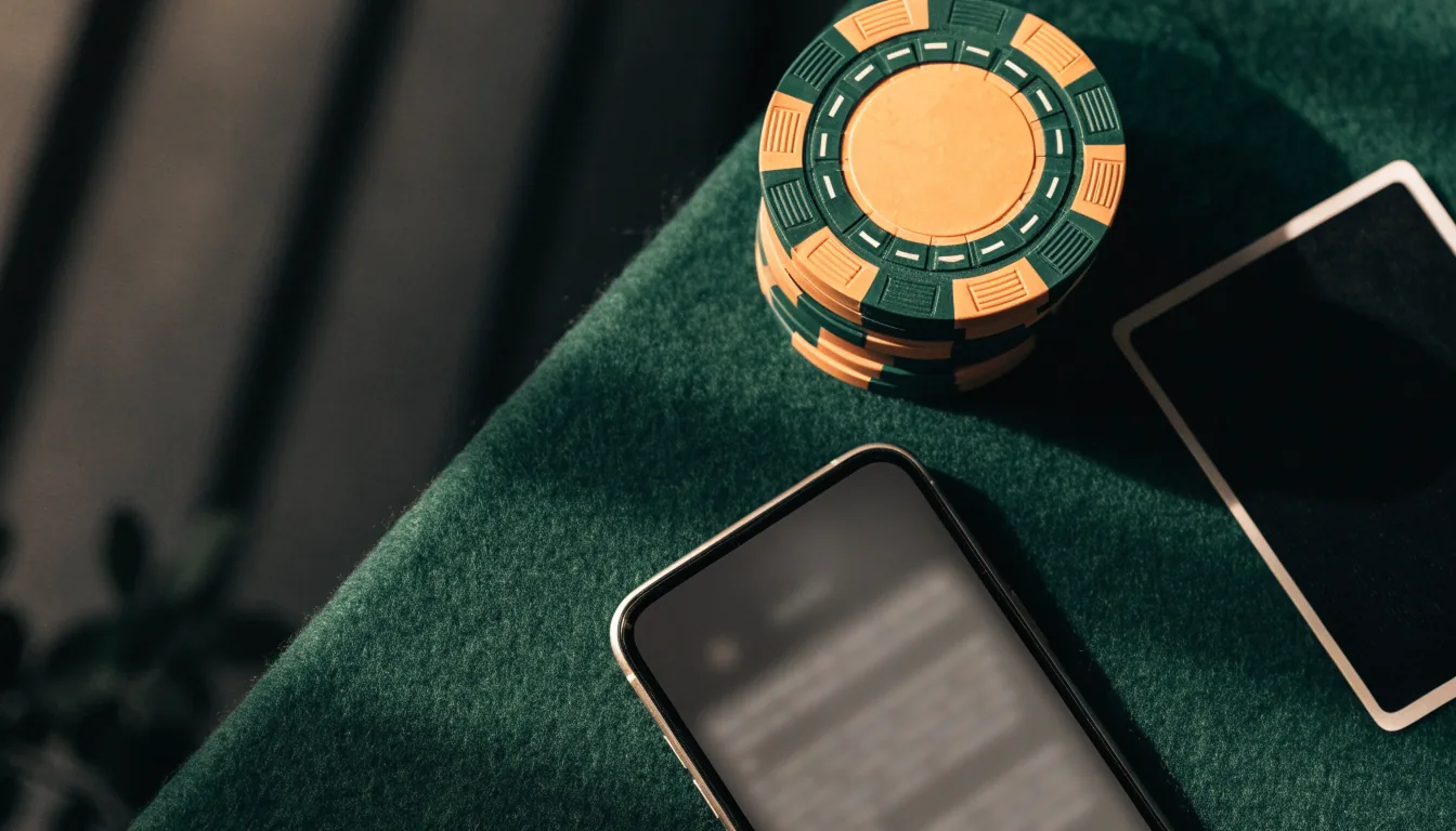 Smartphone met casinofiches en kaarten op groen vilt
